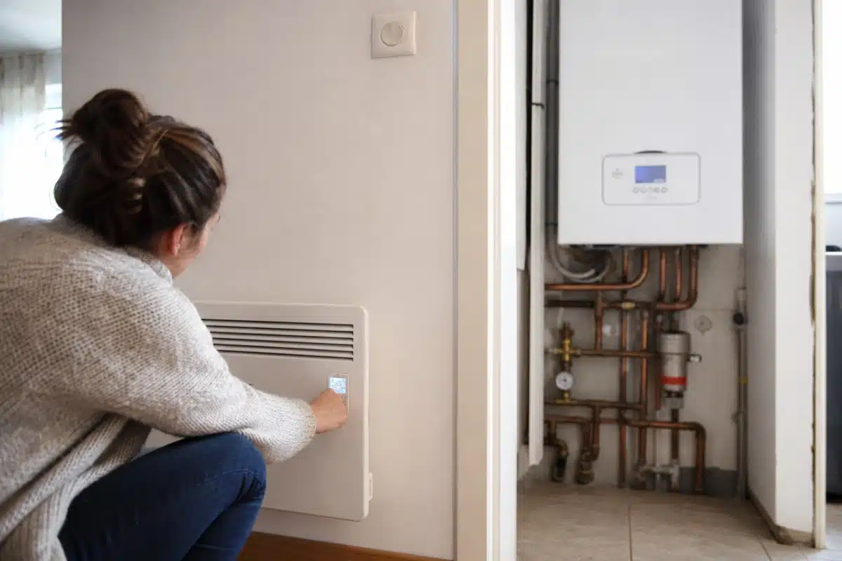 Personne ajustant thermostat près d'une chaudière