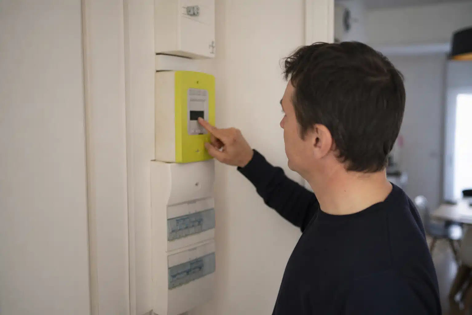 Personne réglant un boîtier compteur électrique mural